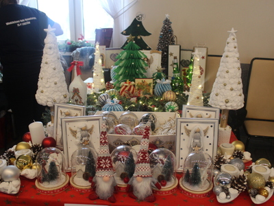 Na zdjęciu stoisko DDP z bliska: choinki, wianki, skrzaty ozdoby w szkle, pudełka upominkowe, bombki, anioły.
