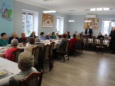 3)	Na fotografii wszyscy goście oraz seniorzy siedzący przy stołach w Domu Dziennego Pobytu. Do zebranych przemawia burmistrz oraz dyrektor mgops w Sompolnie