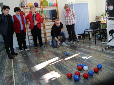 Zdjęcie przedstawia graczy na sali rehabilitacyjnej, którzy rzucają kule do boccie