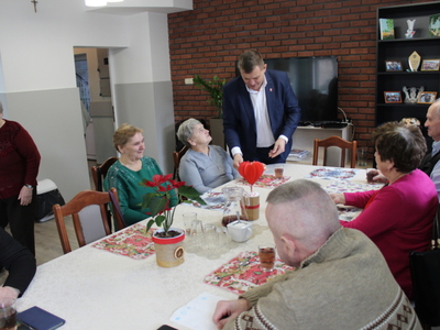 Na fotografii burmistrz Sompolna podaje jednej z seniorek talerz z pączkami