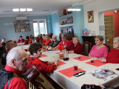 Na zdjęciu seniorzy siedzący przy stole śpiewają piosenki.