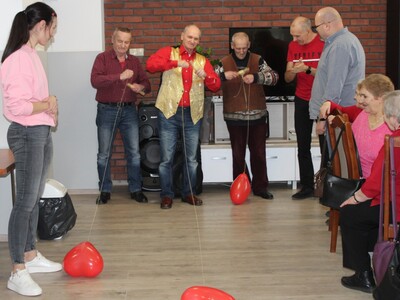 Na zdjęciu trójka panów bierze udział w zabawie – nawijanie balonowego serduszka na drążek.