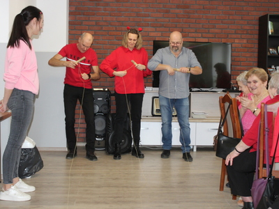 Fotografia przedstawia dyrektora mgops oraz dwójkę opiekunów uczestniczących w zabawie – nawijanie balonowego serduszka na drążek.