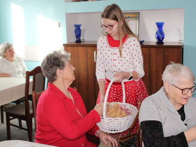 3.	Na zdjęciu znajduje się dziewczynka , która trzyma koszyk i wręcza seniorce upominek