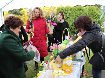 2)	Fotografia przedstawia  uczestników Kiermaszu Wielkanocnego, oraz wystawców  prezentujących wykonane dzieła.