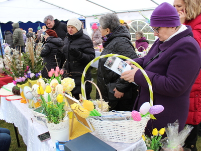 4)	Zdjęcie przedstawia uczestników Kiermaszu Wielkanocnego oglądających prace wystawione na stoisku.
