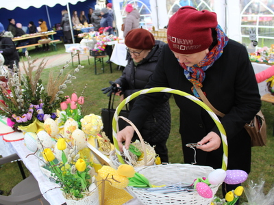 5)	Na zdjęciu widać kobietę- uczestniczkę Kiermaszu Wielkanocnego która ogląda prezentowane na stoiku  prace.