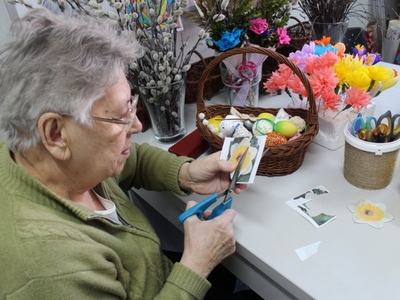 2)	Na zdjęciu jedna z seniorek wycina kwiaty do wiosennej girlandy.