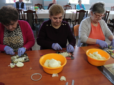 4)	Na zdjęciu trzy uczestniczki warsztatów kulinarnych krojące cebulę.