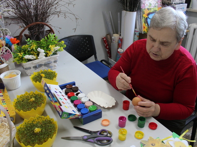 7)	Na zdjęciu seniorka w czerwonej bluzce maluje jajko.