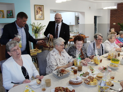 5)	Na fotografii burmistrz wraz z dyrektorem wręczają upominki seniorom.