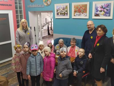 2)	Zdjęcie wykonane w Domu Dziennego Pobytu. Ukazuje dzieci, seniorów, przedstawicieli biblioteki i dyrektora MGOPS w Sompolnie  z żonkilami dla upamiętnienia powstania w getcie warszawskim.