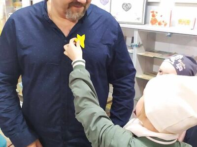 5)	Na zdjęciu dziecko przypina dyrektorowi mgops papierowego żonkila.