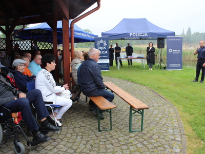 3.	Zdjęcie przedstawia stoisko oraz namiot Komendy Powiatowej Policji w Poznaniu oraz policjanta przemawiającego do grupy seniorów.