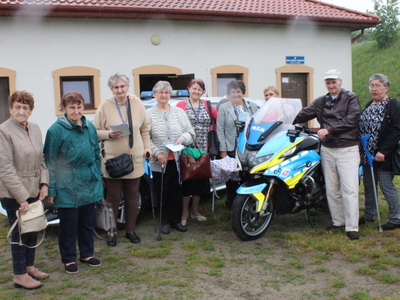 6.	Na pierwszym planie zdjęcia widzimy seniorów stojących przy policyjnych pojazdach zmotoryzowanych