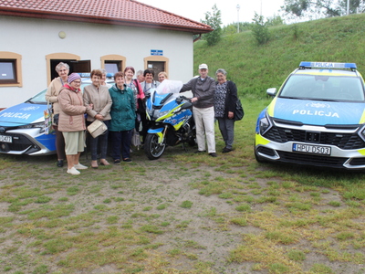 7.	Na pierwszym planie zdjęcia widzimy seniorów stojących przy policyjnych pojazdach zmotoryzowanych