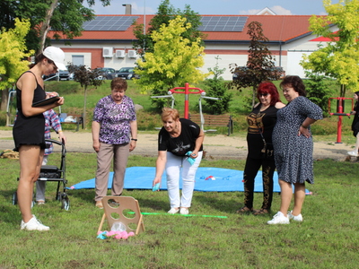 9. Na zdjęciu fizjoterapeutka notująca wyniki konkursu – rzuty do tablicy. Obok niej uczestniczki zabawy