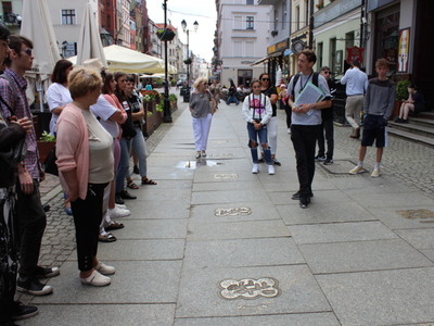 7)	Uczestnicy wycieczki słuchają przewodnika opowiadającego o ulicy piernikowej.