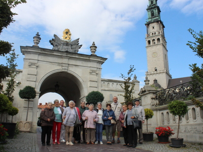 5)	Na fotografii seniorzy na tle bramy wiodącej na Jasną Górę