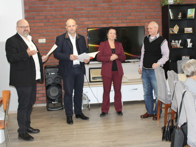 1)	Zdjęcie wykonane w sali głównej Domu Dziennego Pobytu dla Osób Starszych w Sompolnie. Przedstawia od lewej: pana Tomasza Majewskiego – dyrektora MGOPS w Sompolnie, pana Waldemara Marciniaka – burmistrza miasta Sompolna, panią Anetę Niestrawską  - kierowniczkę administracyjną urzędu miejskiego w Sompolnie oraz pana Zygmunta Teodorczyka – uczestnika DDP