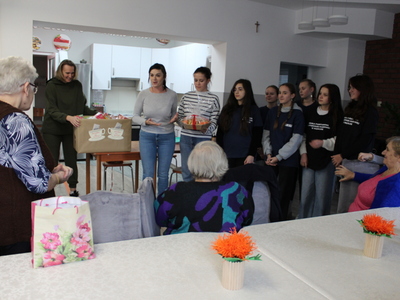 2)	Zdjęcie przedstawia wolontariuszki ze szkoły w Mąkolnie wraz z nauczycielkami. Jedna z nich trzyma kartonik z ciasteczkami upieczonymi dla seniorów w ramach podziękowania za wykonane kotyliony.