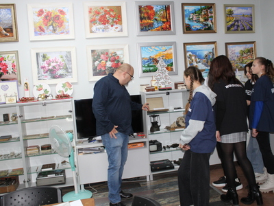 5)	Na zdjęciu dyrektor Miejsko – Gminnego Ośrodka Pomocy Społecznej oprowadza wolontariuszki po placówce. Prezentuje witrynę z antykami.