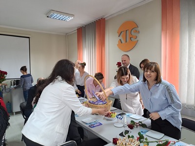 3)	Zdjęcie przedstawia kierownik administracyjną częstującą pracowników czekoladami.