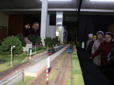 Na zdjęciu zbliżenie makiety. W tle osoby uczestniczące w prezentacji oraz właściciel makiety.