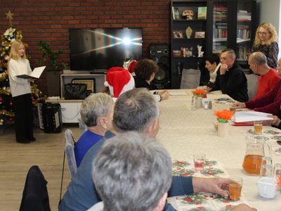 2. Zdjęcie przedstawia występ uczennicy, która śpiewa kolędy przed widownią złożoną z seniorów z DDP