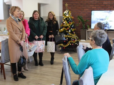 1.	Zdjęcie wykonane w sali głównej DDP. Przedstawia cztery kobiety wręczające seniorom upominki.