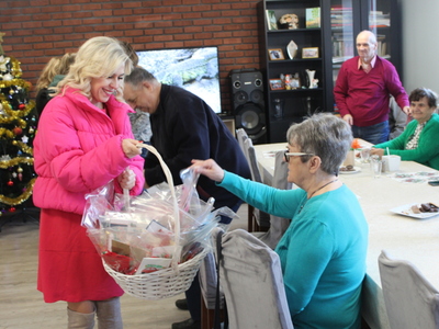 3.	Na zdjęciu widać Seniorkę wyjmującą upominek z koszyka z prezentami.