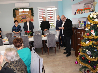 2)	Na fotografii goście zaproszeni na spotkanie wigilijne do seniorów. Z prawej strony dyrektor mgops czytający fragment Pisma Swiętego.