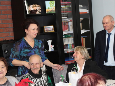 6)	Na zdjęciu pani sekretarz gminy stojąca wśród uczestników siedzących przy stole