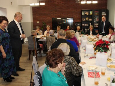 7)	Zdjęcie przedstawia burmistrza i sekretarz gminy stojących przy uczestnikach domu dziennego pobytu