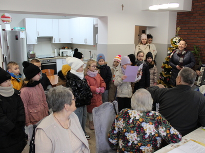 1)	Zdjęcie wykonane na sali głównej DDP. Przedstawia grupę dzieci, które przyszły do seniorów.