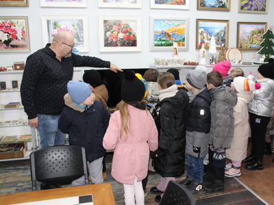 6)	Na zdjęciu dyrektor mgops w Sompolnie prezentujący dzieciom gablotę z antykami.