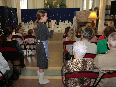 1)	Zdjęcie wykonane w miejsko – gminnej bibliotece publicznej w Sompolnie. Przedstawia dziewczynę chodzącą wśród publiczności z mikrofonem w dłoni. W tle scenografia do spektaklu „Dziewczynka z zapałkami”.