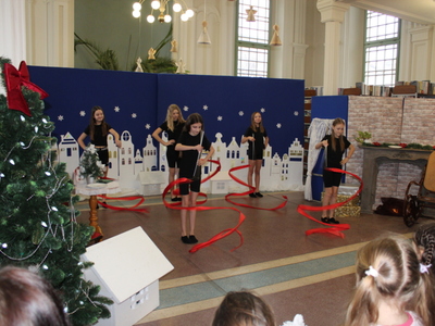 5)	Zdjęcie przedstawia pięć dziewczynek w czarnych strojach gimnastycznych tańczących z czerwonymi wstążkami do tańca.