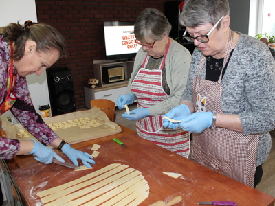 2) Na zdjęciu dwie uczestniczki i opiekunka terapii kulinarnej formują chruściki.