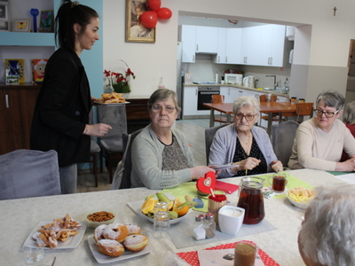 6) Na zdjęciu seniorzy siedzący przy zastawionym stole w Tłusty Czwartek.