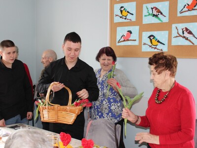 4. Na zdjęciu widzimy chłopców podchodzących do Seniorki by wręczyć jej kwiatka