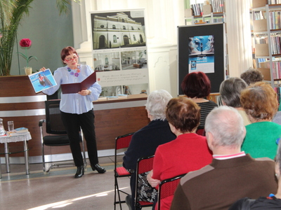 4) Zdjęcie przedstawia Panią Dorotę Grzechowiak – konińską pisarkę, stojącą przed publicznością z książką w jednej dłoni i zdjęciem delfina w drugiej.