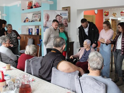 Na zdjęciu jedna z uczestniczek ddp siedząca na wózku elektrycznym. Wokół seniorzy z ddp oraz pracownicy mgops w sompolnie.