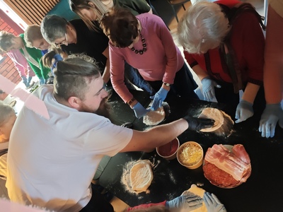 Na zdjęciu seniorzy wykonujący samodzielnie pizze podczas warsztatów kulinarnych