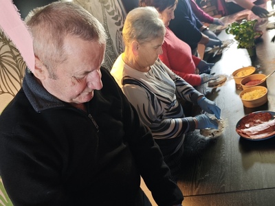 Zdjęcie przedstawia jednego seniora wyrabiającego ciasto na pizze