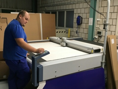 Na zdjęciu znajduje się mężczyzna stojący przy dużym ploterze.