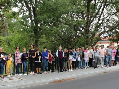15)	Zdjęcie przedstawia wszystkich uczestników marszu nordic walking stojących na moście przy ulicy 11 Listopada w Sompolnie.