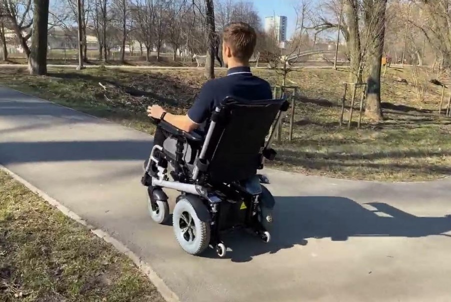 Zdjęcie przedstawia mężczyznę jadącego na wózku inwalidzkim