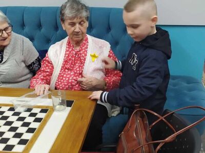 Na zdjęciu chłopiec przypina seniorce żonkila.