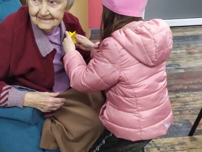 Na zdjęciu dziewczynka przypina seniorce żonkila.